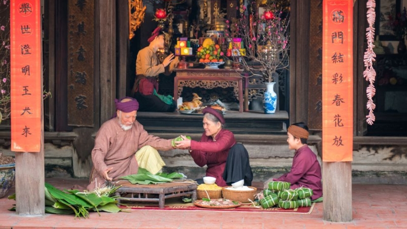 Ông bà cùng cháu gói bánh chưng để chuẩn bị cho mâm cỗ Tết truyền thống