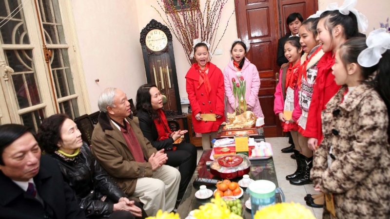 Cháu nhỏ đang đọc thơ chúc Tết cho ông bà nghe trong không khí ấm áp ngày xuân